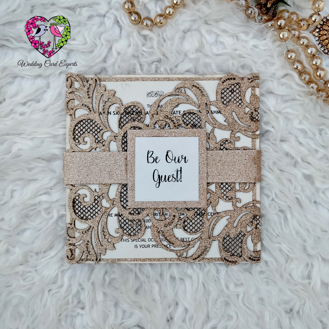 Glitter gold laser cut gatefold wedding invitation with floral cutwork and Be Our Guest tag