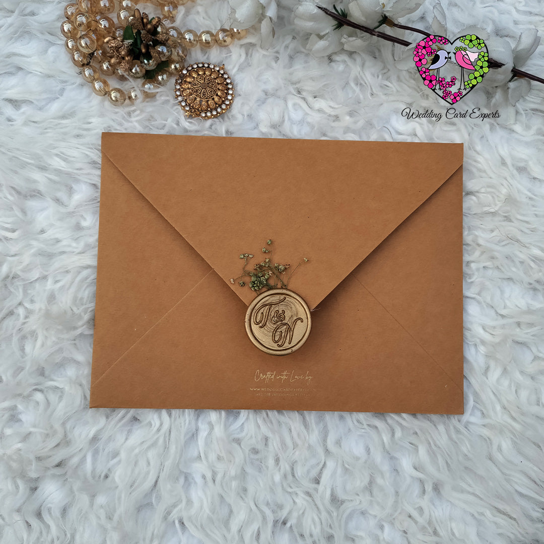 Brown envelope with a wax seal on a white textured surface, with 'Wedding Card Experts' logo in the corner. Wedding Cards Pakistan, Pakistani Wedding Cards