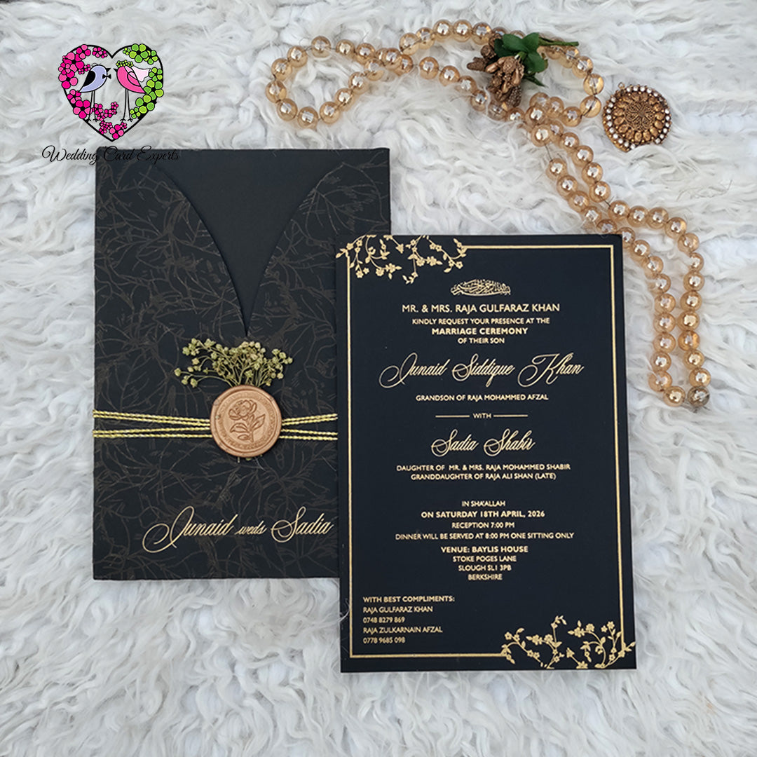 Wedding card design Pakistan — matte black botanical V-flap folder with gold script names and copper wax seal beside full black gold printed invitation card, Wedding Card Experts DHA Lahore