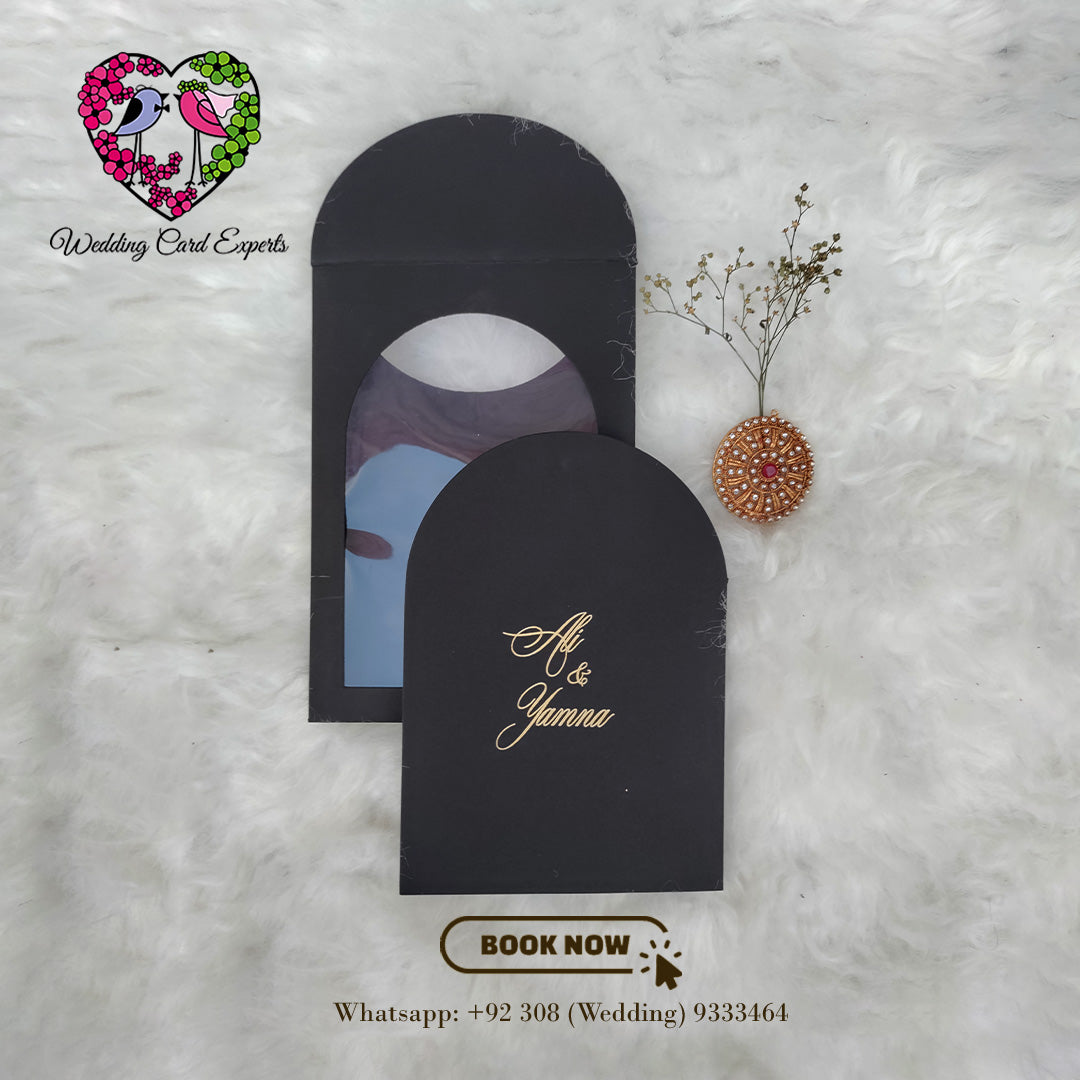 Wedding cards Pakistan — black matte arch sleeve with gold foil couple names and circular cut-out window, Pakistani wedding invitation card design by Wedding Card Experts DHA Lahore