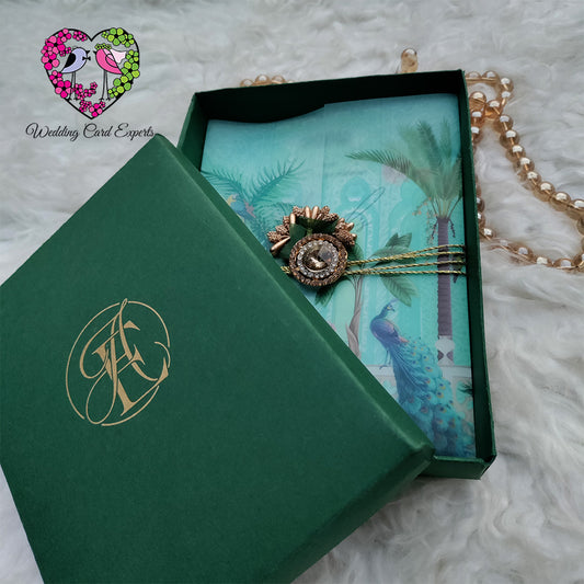Green Box Wedding card with jewelry and decorative brooch on a vellum paper wrapped in golden twine