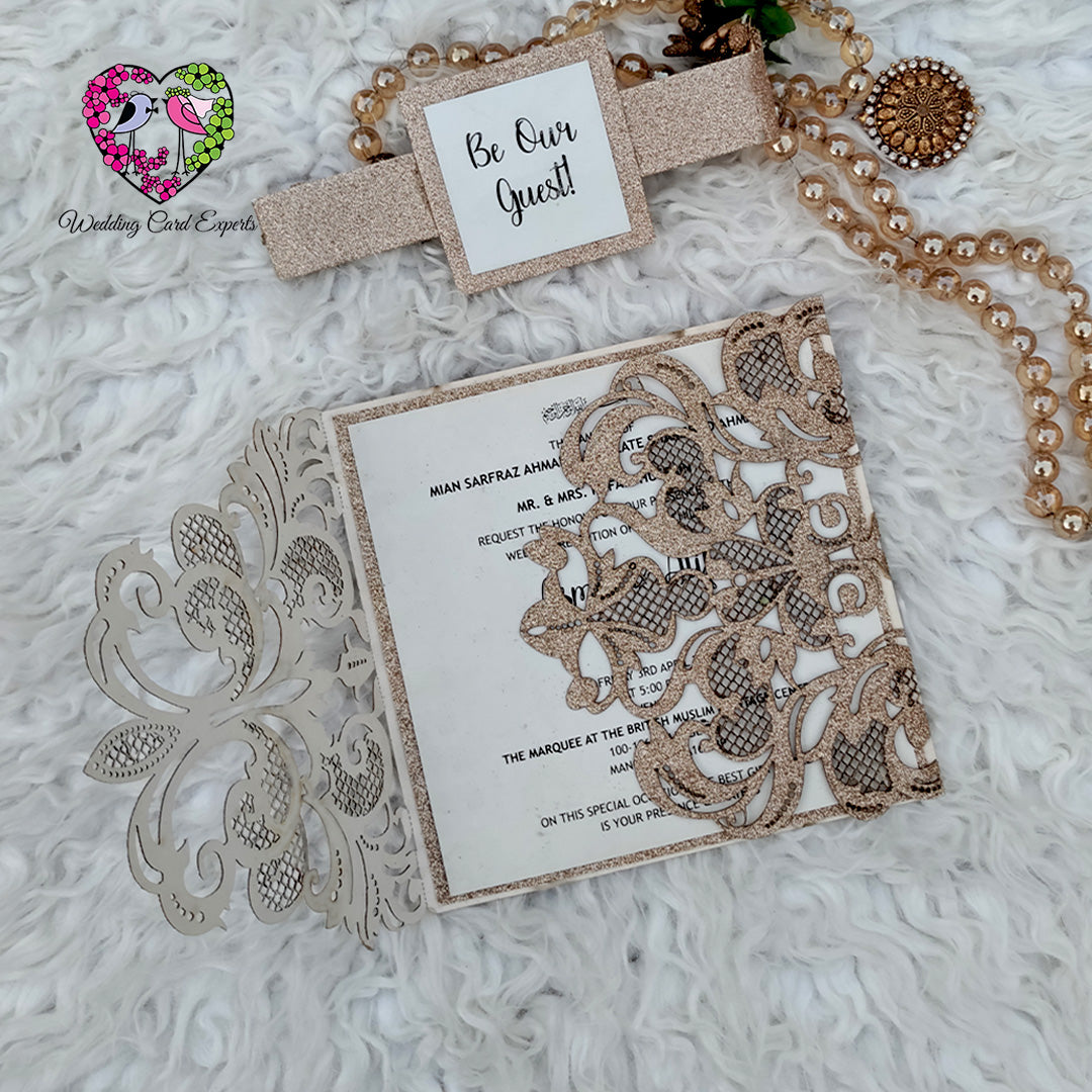 Glitter gold wedding invitation flat lay with pearl jewelry and Be Our Guest belly band