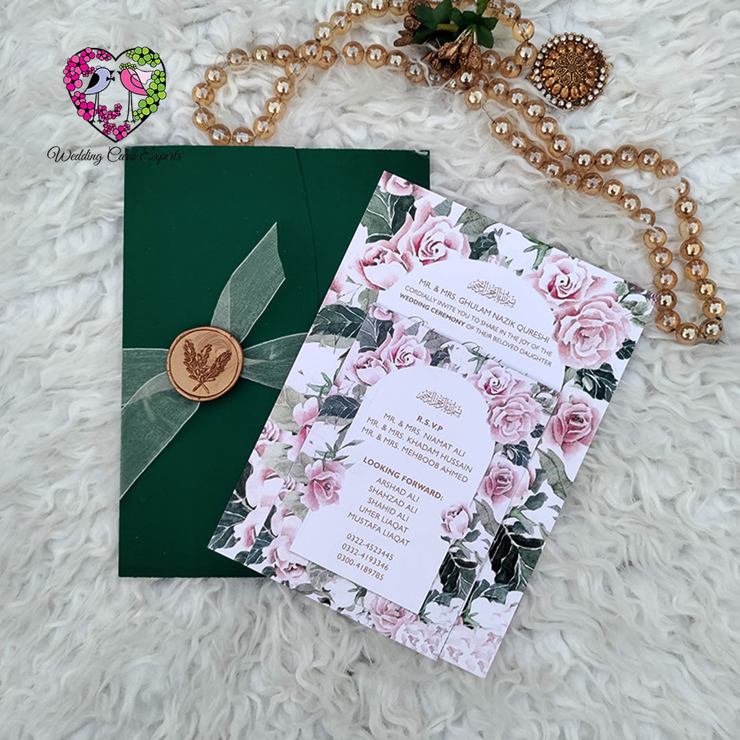 Wedding invitation cards Pakistan — green pocket folder with copper botanical wax seal beside blush pink rose floral main card and RSVP card, Wedding Card Experts DHA Lahore
