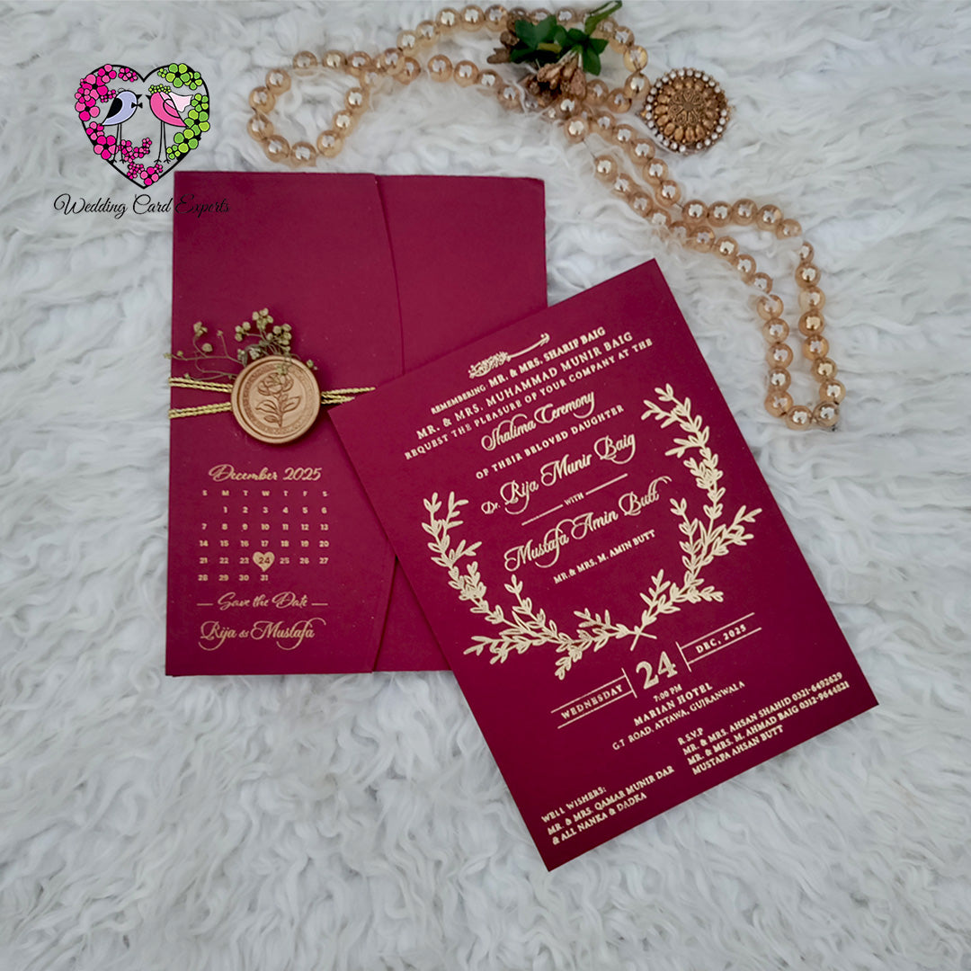 Luxury wedding cards Pakistan — deep burgundy textured gold foil pocket folder with copper rose wax seal, save the date calendar reverse and dried baby's breath, Wedding Card Experts DHA Lahore
