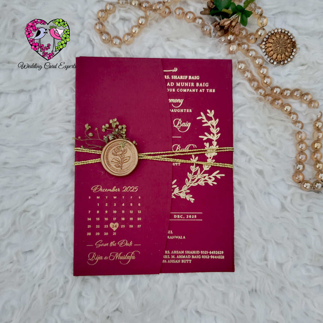 Luxury Pakistani wedding card — burgundy textured gold foil laurel wreath invitation with botanical sprig detailing and save the date reverse, premium wedding cards Pakistan Lahore