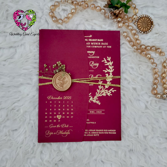 Luxury Pakistani wedding card — burgundy textured gold foil laurel wreath invitation with botanical sprig detailing and save the date reverse, premium wedding cards Pakistan Lahore