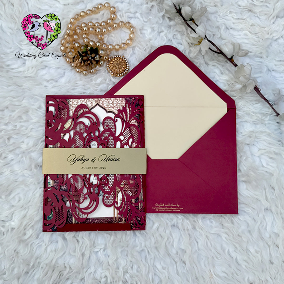 Closed burgundy gatefold wedding card with gold belly band, personalised names and matching ivory-lined burgundy envelope